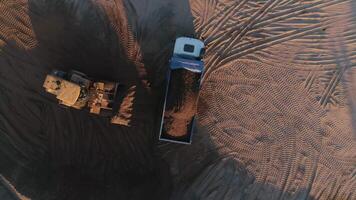 Sand mining industry, sand mine at the quarry. Scene. Aerial top view of a bulldozer machine putting sand to the truck body. video