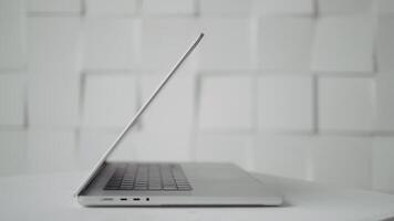 Side view of new laptop on white background. Action. Beautiful laptop on table. Laptop open at angle for advertising insert video