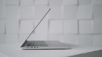 kant visie van een nieuw modern wit laptop aan het liegen Aan een tafel oppervlakte tegen de muur. actie. werken van huis, concept van freelancer. video