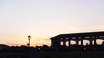 Sunset landscape with arched building and lanterns. Action. Beautiful horizon with dark silhouettes of buildings and glowing lanterns. Panorama of arched building on background of twilight video