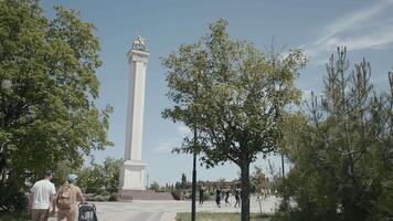 turisti camminare nel città parco con monumento per guerriero. azione. bellissimo vivace vittoria parco con monumento e danza gruppo. camminare nel vittoria parco su soleggiato giorno video