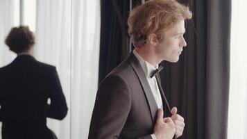 A man with a sympathetic appearance . Action . A man in an elegant suit stands next to the mirror and poses. video