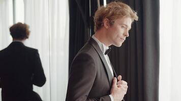 A man with a sympathetic appearance . Action . A man in an elegant suit stands next to the mirror and poses. video