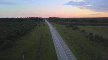 parte superior ver de coche conducción a lo largo bosque autopista a amanecer. acortar. hermosa panorama de partiendo coche en antecedentes de horizonte a amanecer. bosque pista con coche a amanecer video