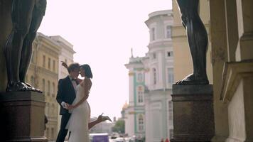 Fototermin von ein schön elegant Hochzeit Paar Innerhalb das Veranda von das Neu Einsiedelei durch das Füße von Atlanten. Aktion. liebend Braut und Bräutigam Umarmen beim das historisch Center von Heilige Peterburg video