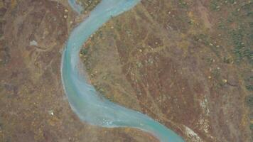 Top view of winding blue river. Clip. Beautiful blue river flows in deserted area. Blue river with beautiful winding paths video