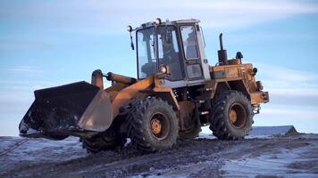 besneeuwd het weer, graafmachine graven bevroren grond. klem. zwaar industrie concept, machine Bij de mijne werk Aan blauw lucht achtergrond. video