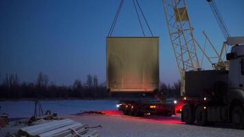 Prozess von Entladung ein LKW Auto mit ein Kran und Metall Kabel im das Abend. Clip. Ladung LKW Container Entladung. video