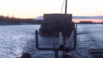 onderdelen van een lading schip. clip.a groot schip met een aanhangwagen dat beweegt ontwikkelen golven Aan de rivier- en draagt lading Aan een donker avond met een mooi zonsondergang en een Purper achtergrond. video