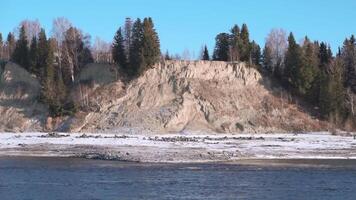 Natural landscape with a river in early winter and a hilly shore covered by trees. Clip. Stone cliff with forest and cold river. video