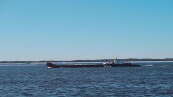 A snowy sea with ships.Clip. Huge ships with cargo move through the snowy sea, behind which the forest is visible. video