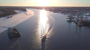 View from a helicopter.Clip. A spring landscape where large ships export cargo along the river next to bare slightly snowy forests. video