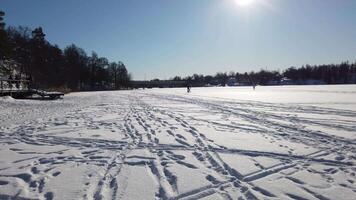 People stroll and a man rides a bicycle leisurely on the frozen lake during a sunny morning in Scandinavia video