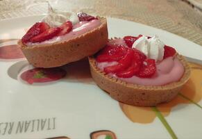 two strawberry cheesecakes are on a plate photo