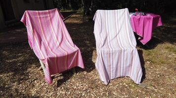 4K of two beach towels drying on chairs and a table on which there are more towels and a diving mask video