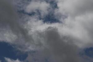 Cloudscape scenery, overcast weather above dark blue sky. Storm clouds floating in a rainy dull day with natural light. White and grey scenic environment background. Nature view. photo