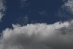 Cloudscape scenery, overcast weather above dark blue sky. Storm clouds floating in a rainy dull day with natural light. White and grey scenic environment background. Nature view. photo