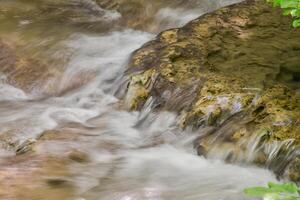 Mountain stream in the forest - long exposure and flowing water photo