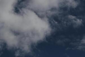 Cloudscape scenery, overcast weather above dark blue sky. Storm clouds floating in a rainy dull day with natural light. White and grey scenic environment background. Nature view. photo