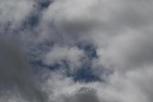 Cloudscape scenery, overcast weather above dark blue sky. Storm clouds floating in a rainy dull day with natural light. White and grey scenic environment background. Nature view. photo