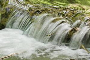 Mountain stream in the forest - long exposure and flowing water photo