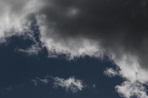 Cloudscape scenery, overcast weather above dark blue sky. Storm clouds floating in a rainy dull day with natural light. White and grey scenic environment background. Nature view. photo