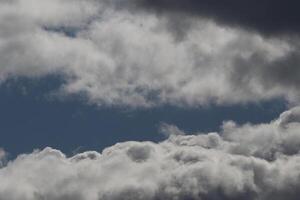 Cloudscape scenery, overcast weather above dark blue sky. Storm clouds floating in a rainy dull day with natural light. White and grey scenic environment background. Nature view. photo