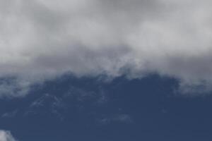 Cloudscape scenery, overcast weather above dark blue sky. Storm clouds floating in a rainy dull day with natural light. White and grey scenic environment background. Nature view. photo