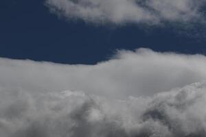 Cloudscape scenery, overcast weather above dark blue sky. Storm clouds floating in a rainy dull day with natural light. White and grey scenic environment background. Nature view. photo