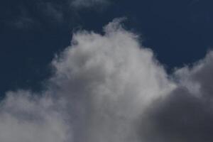 Cloudscape scenery, overcast weather above dark blue sky. Storm clouds floating in a rainy dull day with natural light. White and grey scenic environment background. Nature view. photo