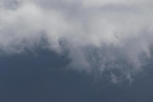 Cloudscape scenery, overcast weather above dark blue sky. Storm clouds floating in a rainy dull day with natural light. White and grey scenic environment background. Nature view. photo
