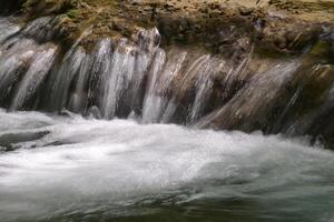 Mountain stream in the forest - long exposure and flowing water photo