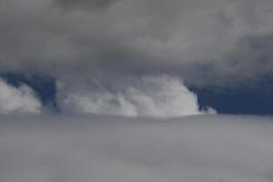 Cloudscape scenery, overcast weather above dark blue sky. Storm clouds floating in a rainy dull day with natural light. White and grey scenic environment background. Nature view. photo