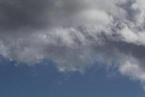 Cloudscape scenery, overcast weather above dark blue sky. Storm clouds floating in a rainy dull day with natural light. White and grey scenic environment background. Nature view. photo