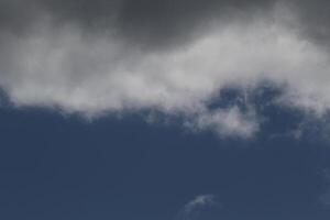 Cloudscape scenery, overcast weather above dark blue sky. Storm clouds floating in a rainy dull day with natural light. White and grey scenic environment background. Nature view. photo