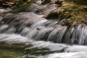 Mountain stream in the forest - long exposure and flowing water photo