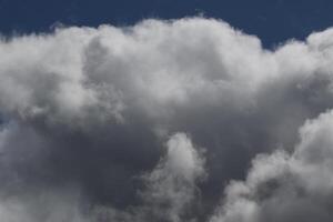Cloudscape scenery, overcast weather above dark blue sky. Storm clouds floating in a rainy dull day with natural light. White and grey scenic environment background. Nature view. photo