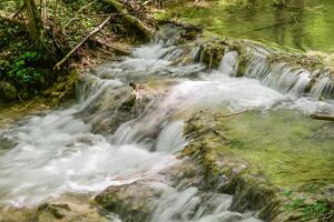 Mountain stream in the forest - long exposure and flowing water photo