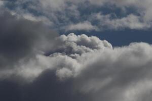 Cloudscape scenery, overcast weather above dark blue sky. Storm clouds floating in a rainy dull day with natural light. White and grey scenic environment background. Nature view. photo