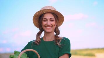 kvinna jordbrukare i sugrör hatt med korg full av grönsaker på jordbruksmark video
