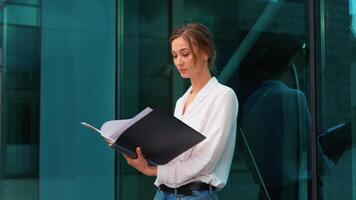Confident businesswoman reading documents outside corporate office video
