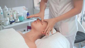 terapeuta fornecendo facial massagem para relaxado mulher dentro clínica video