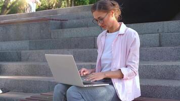 alegre mujer de negocios utilizando ordenador portátil sentado en pasos en parque video