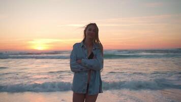 contento donna nel denim camicia a piedi vicino mare a spiaggia durante tramonto video