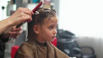 Cute girl getting haircut by female hairdresser in salon video