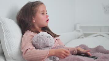 enfermo niña tos mientras sentado con suave juguete en cama a hogar video