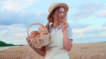 Smiling farmer with basket of freshly baked bread in wheat field video