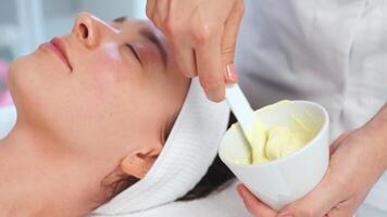 Beautician mixing creamy substance in cup for client in beauty spa video