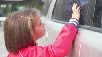 Cute little girl drawing cartoon on dirty window of car video