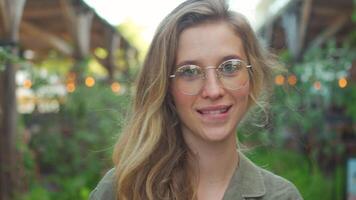 portrait de Jeune femme dans lunettes permanent au milieu de les plantes en plein air video